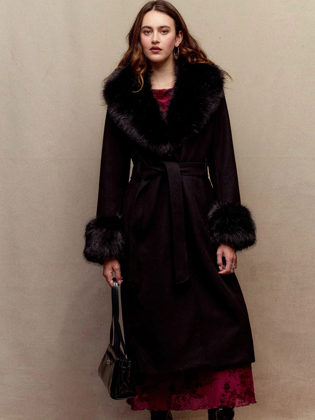 Anastasie black long coat worn belted, faux-fur collar and cuffs